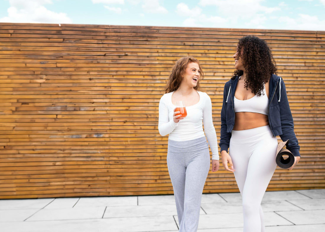 Two women enjoying an active lifestyle outside, one has a yoga mat rolled under her arm